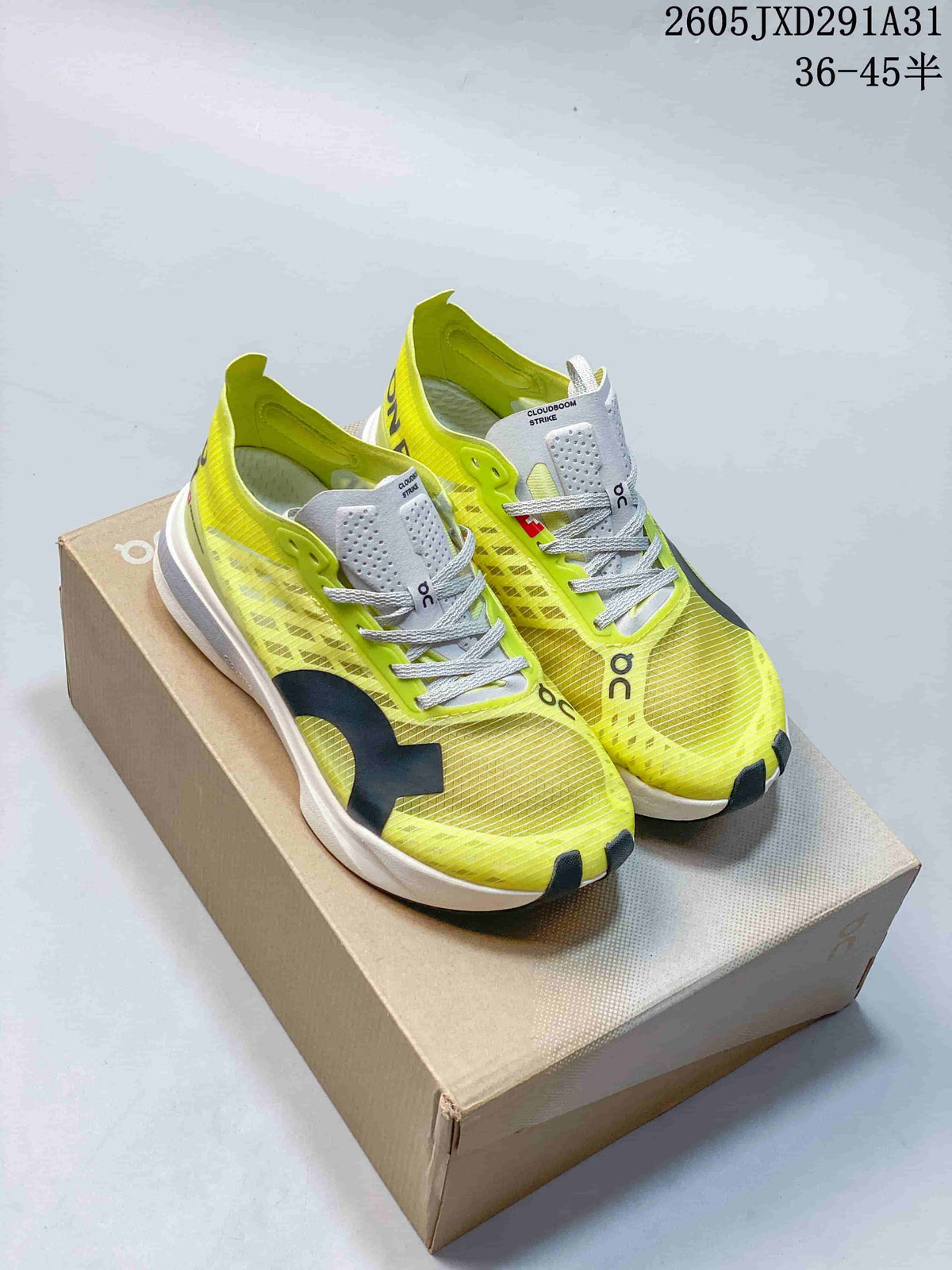 Pair of yellow-green On Cloudboom Strike running shoes displayed on a box.