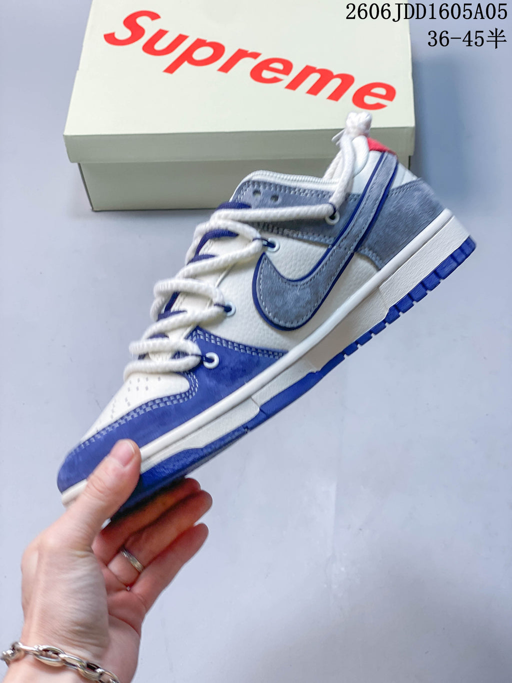 Side profile of a white, blue, and gray low-top sneaker with layered panels and cord laces