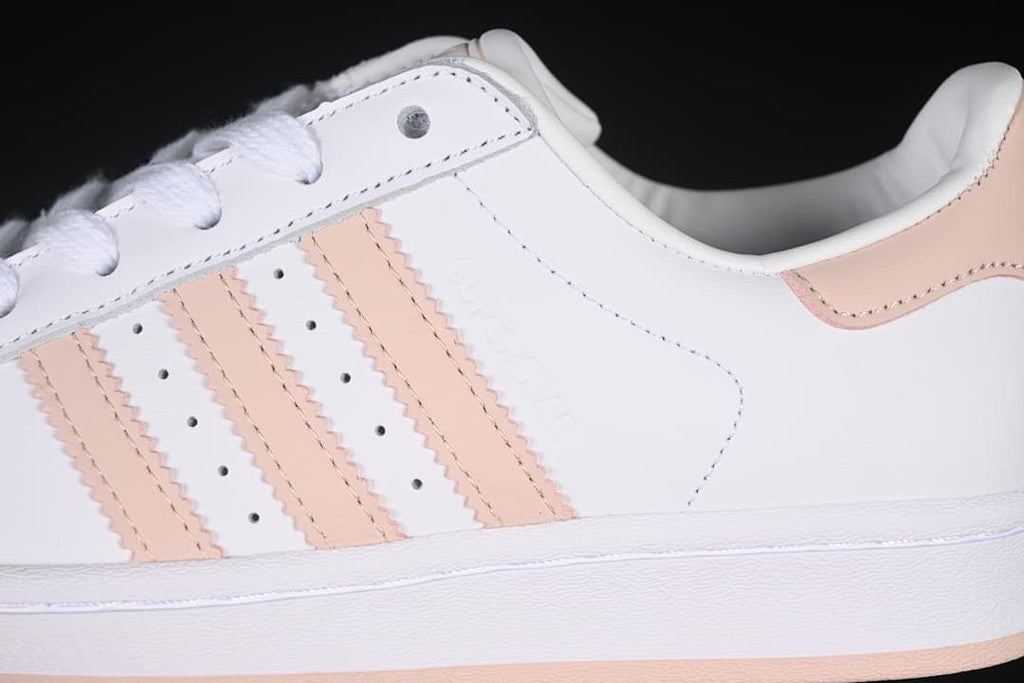 Close-up of the white side panel, blush-pink stripes, perforations, and heel accent.