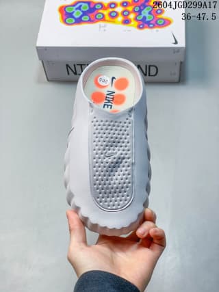 Top view of a white Nike Mind slide showing the perforated upper, covered toe, and orange insole details.