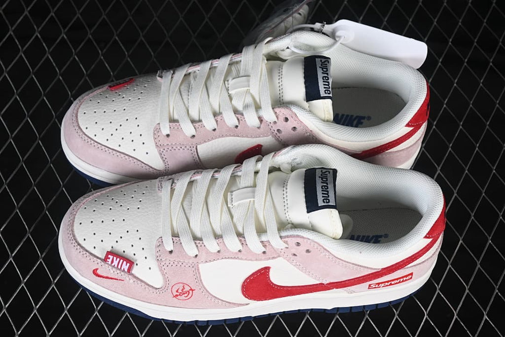 Pair of white, pale pink, and red Nike SB Dunk Low sneakers shown from above