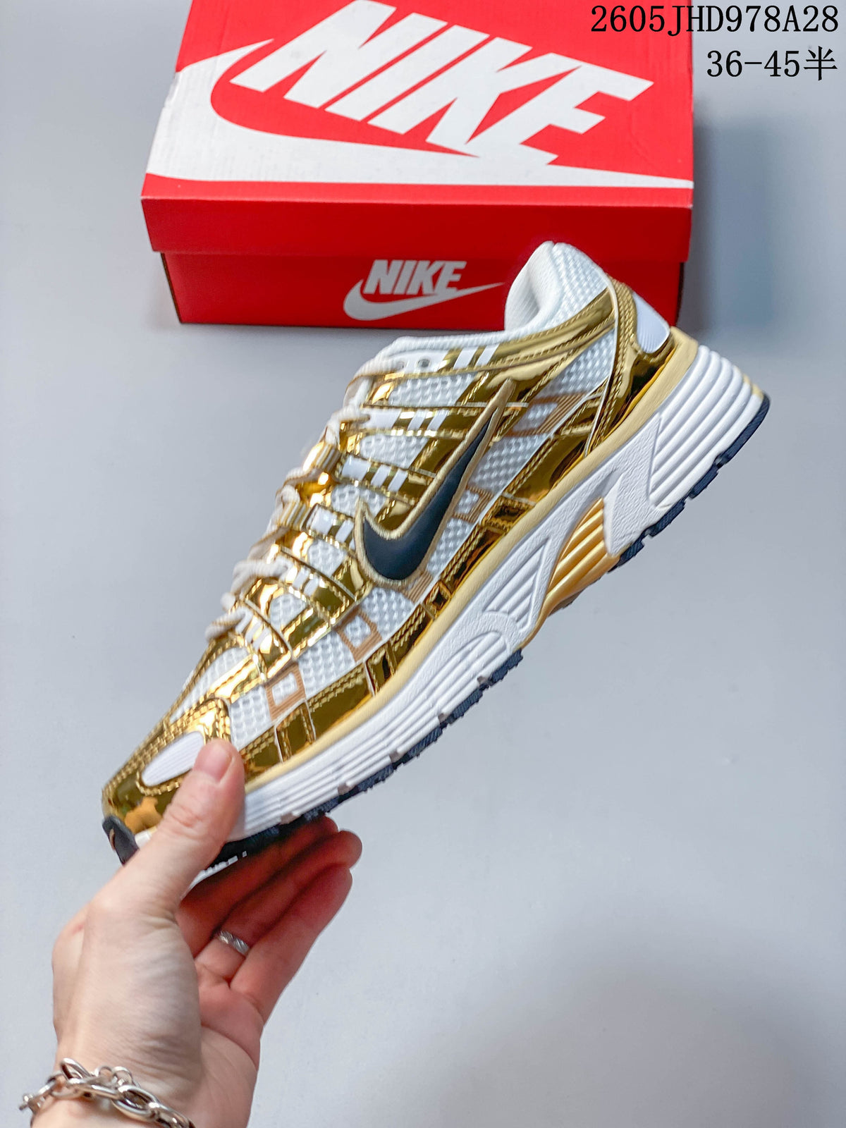 Side profile of the Nike Initiator showing its layered gold-tone overlays and dark Swoosh