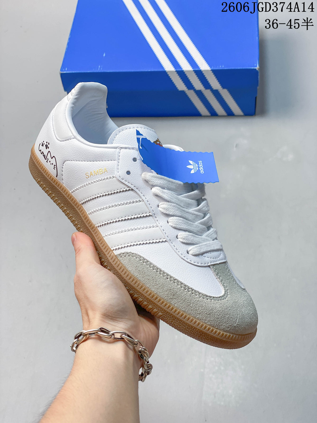 White low-top sneaker with beige detailing, gum sole, and decorative heel graphics.