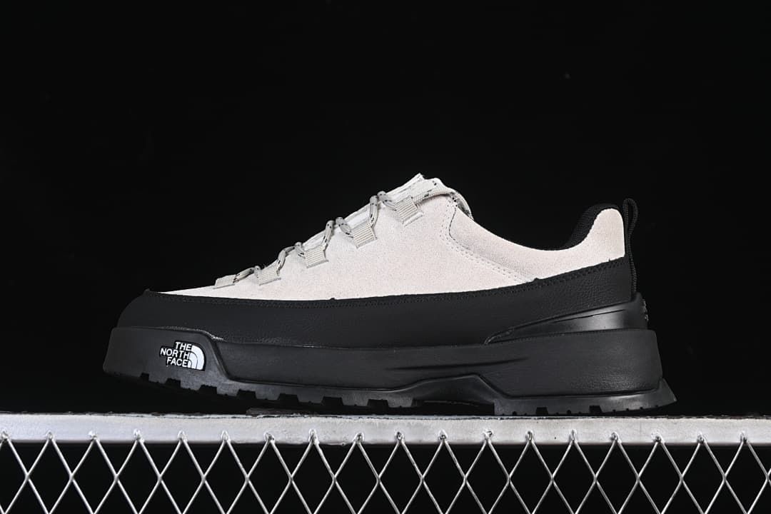 Side view of the light grey and black shoe against a dark background