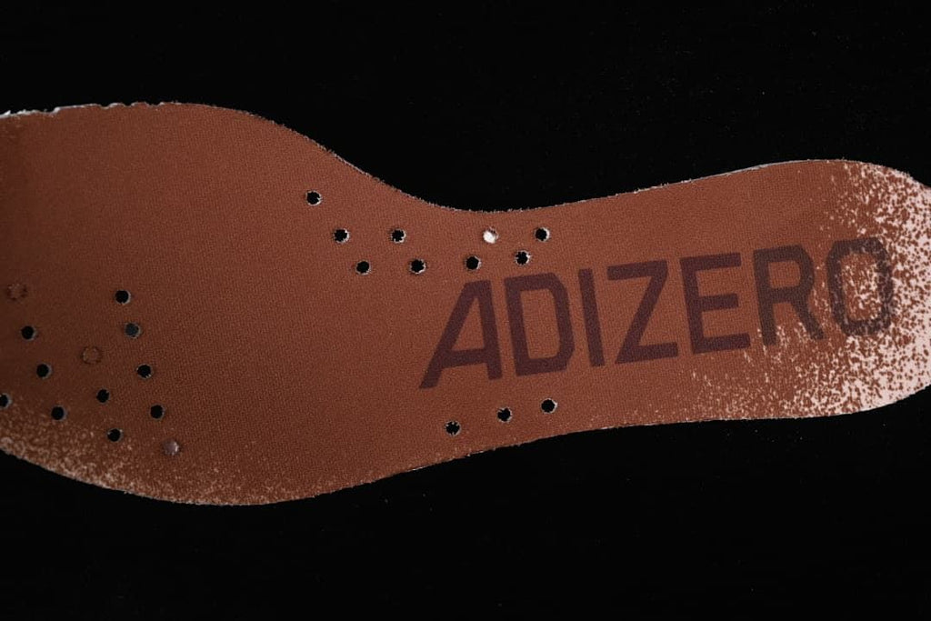 Brown Adizero-branded insole with perforations