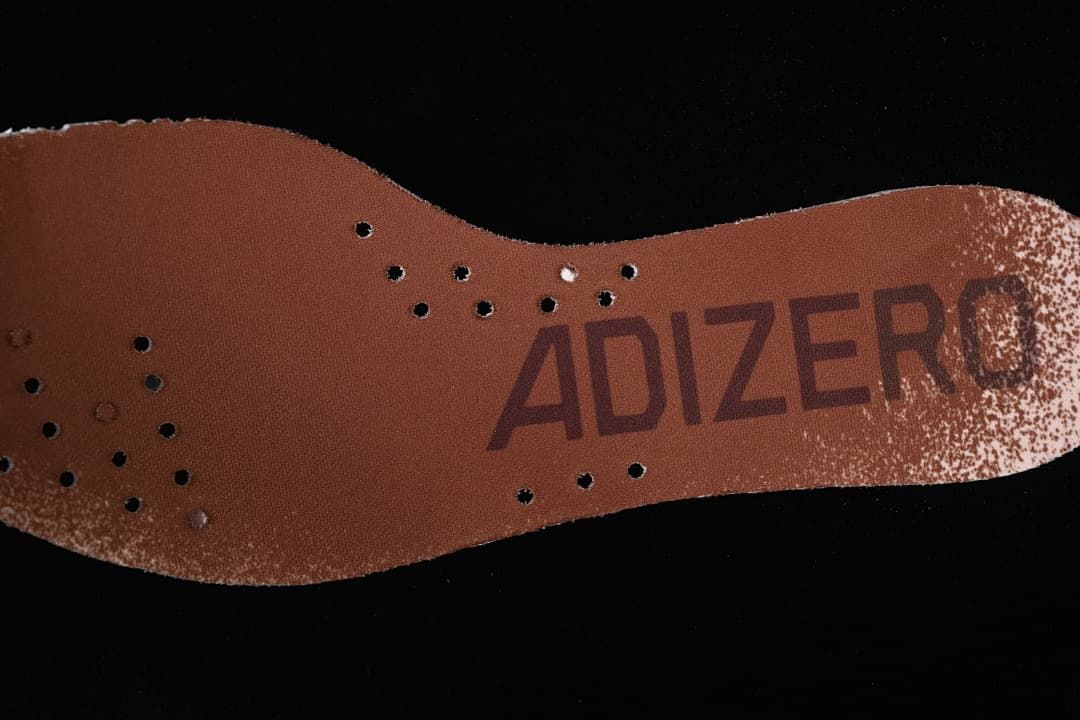 Brown Adizero-branded insole with perforations