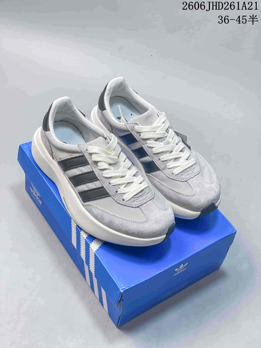Pair of grey adidas Originals SL 72 Pro sneakers with dark stripes, shown on a blue box