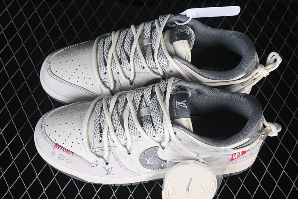Overhead view of a pair of light gray and off-white low-top sneakers with patterned panels and extra laces at the heels.