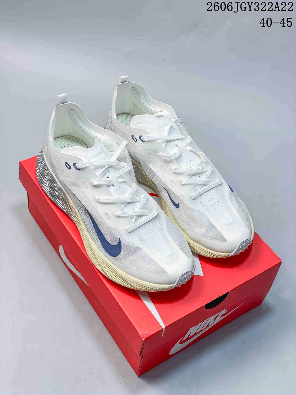 White Nike Ava X low-top shoes with blue Swoosh accents, shown on a red shoebox.