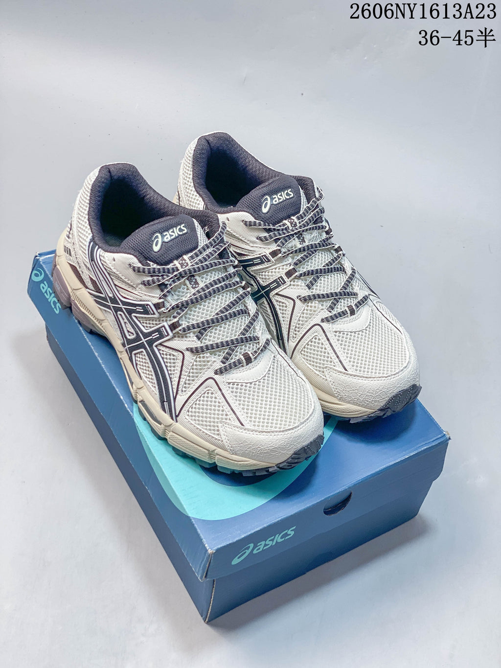 Pair of cream and navy ASICS Gel-Kahana 8 shoes displayed on a blue box