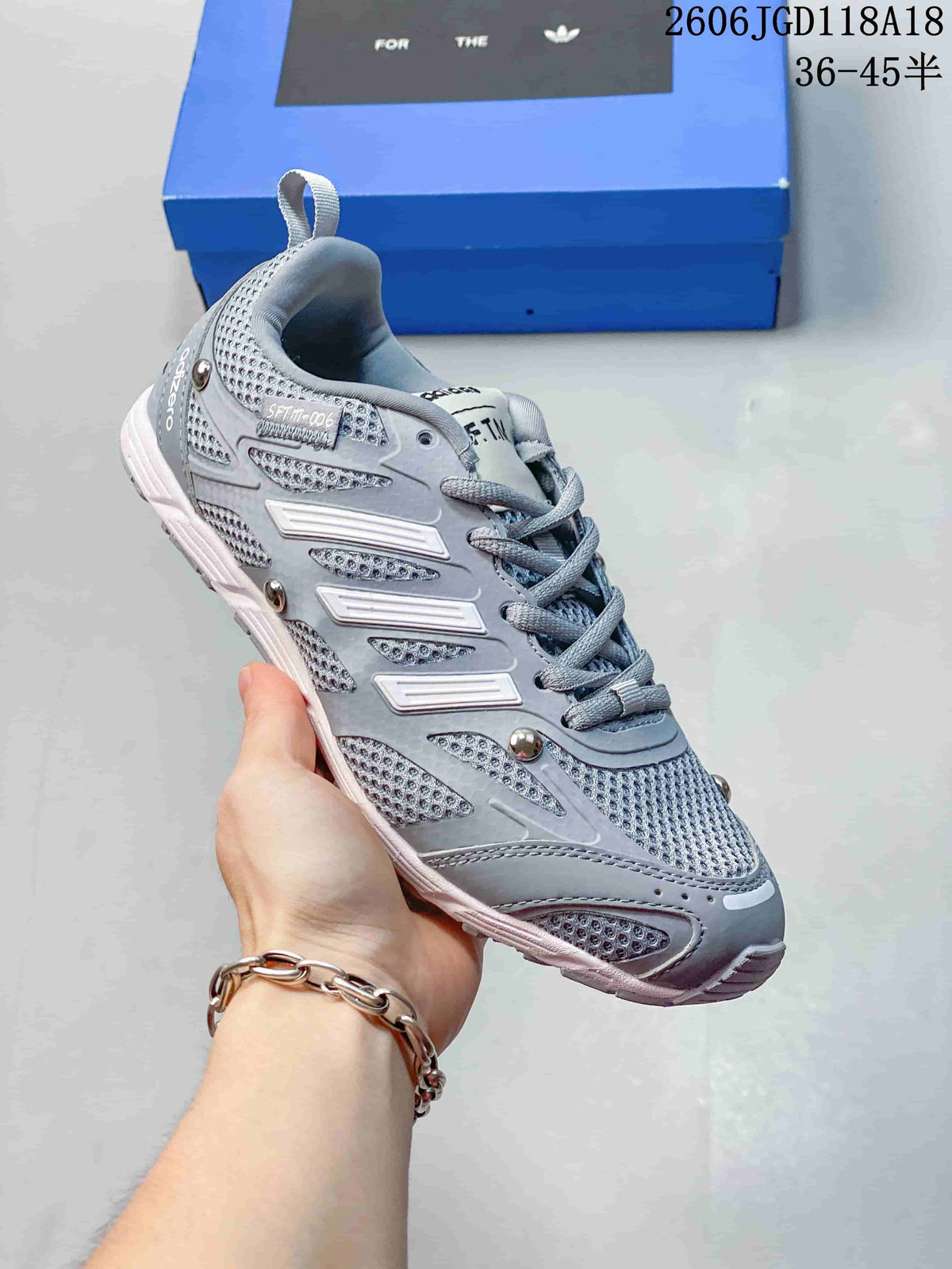 Angled side view of a grey sneaker with three-stripe detailing and metallic-look accents