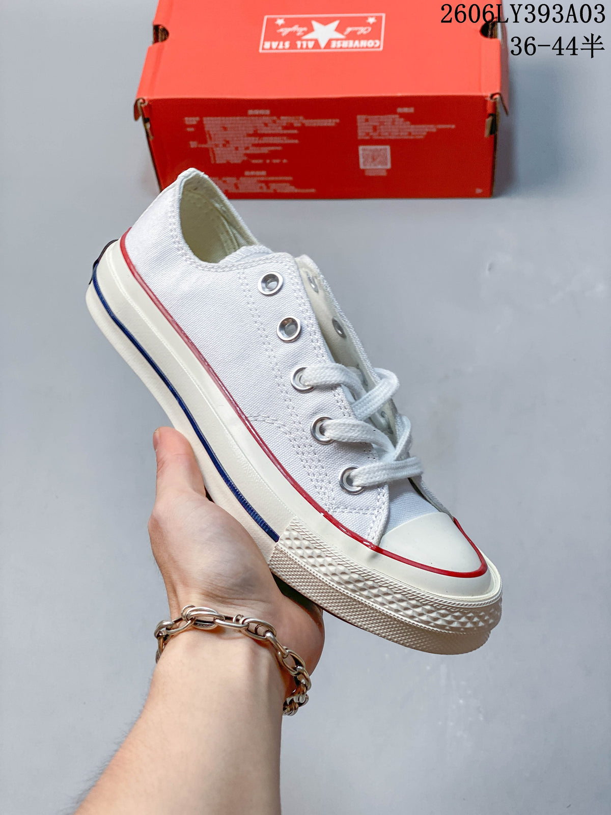 White low-top sneaker with red and blue stripes along the off-white sole