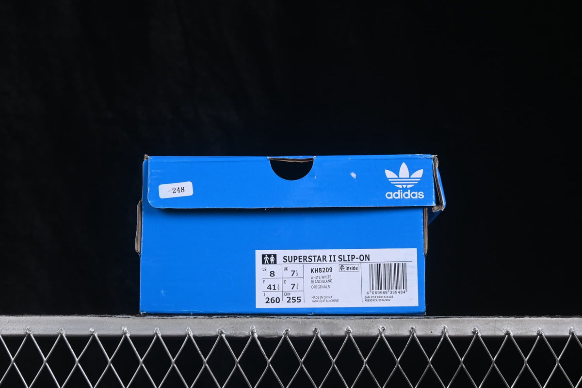 Blue adidas shoe box with a label showing Superstar II Slip-On, style code KH8209, and a photographed sample size.