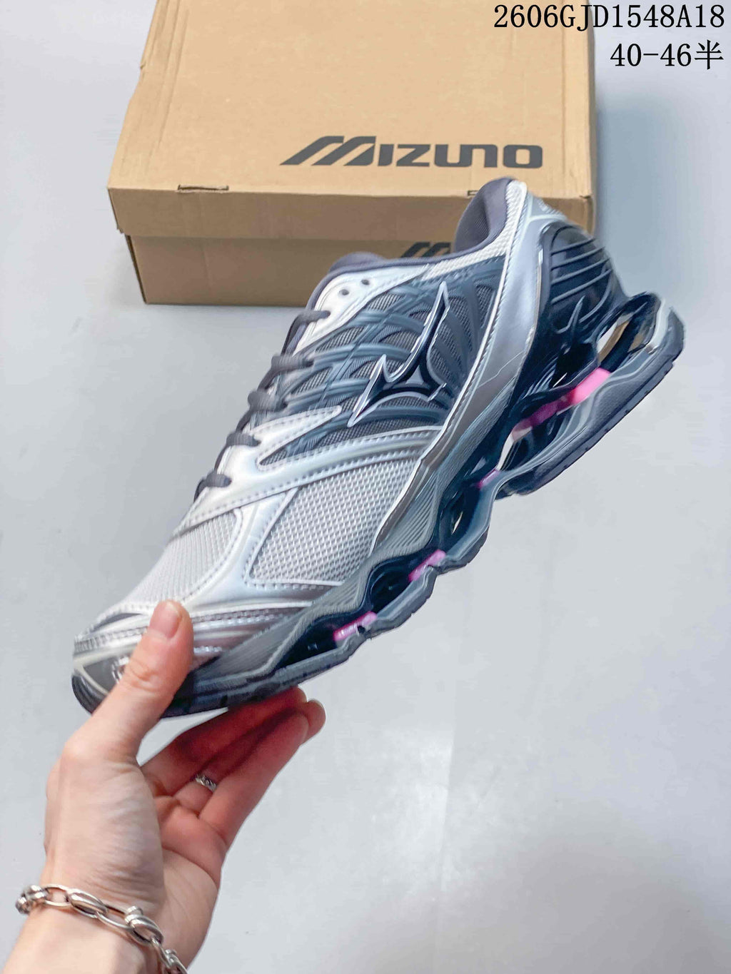 Side view of a silver and gray Mizuno sneaker with pink accents