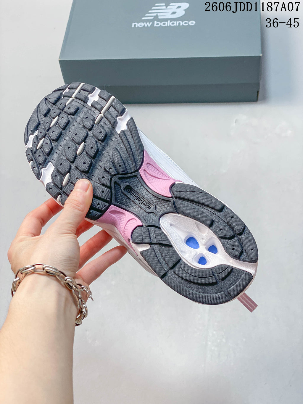 Underside of a New Balance sneaker showing a black, white and pink outsole
