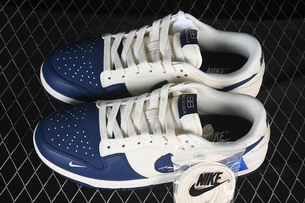 Top view of cream and navy low-top sneakers with perforated toe panels and spare laces