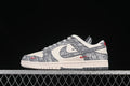 Side view of an ivory and gray low-top Nike SB Dunk with monogram-style panels and red accents