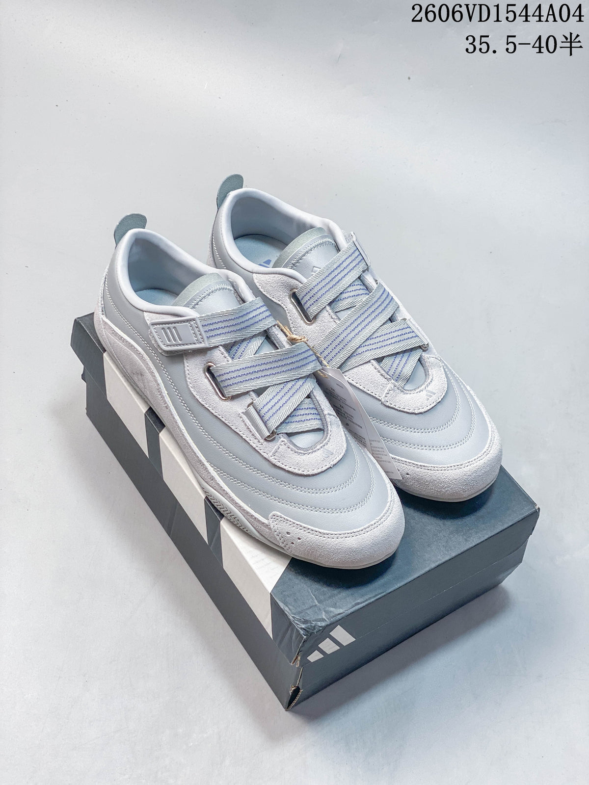 Pair of light gray Adidas Urban Reverie low-top sneakers with striped straps, shown on a shoebox