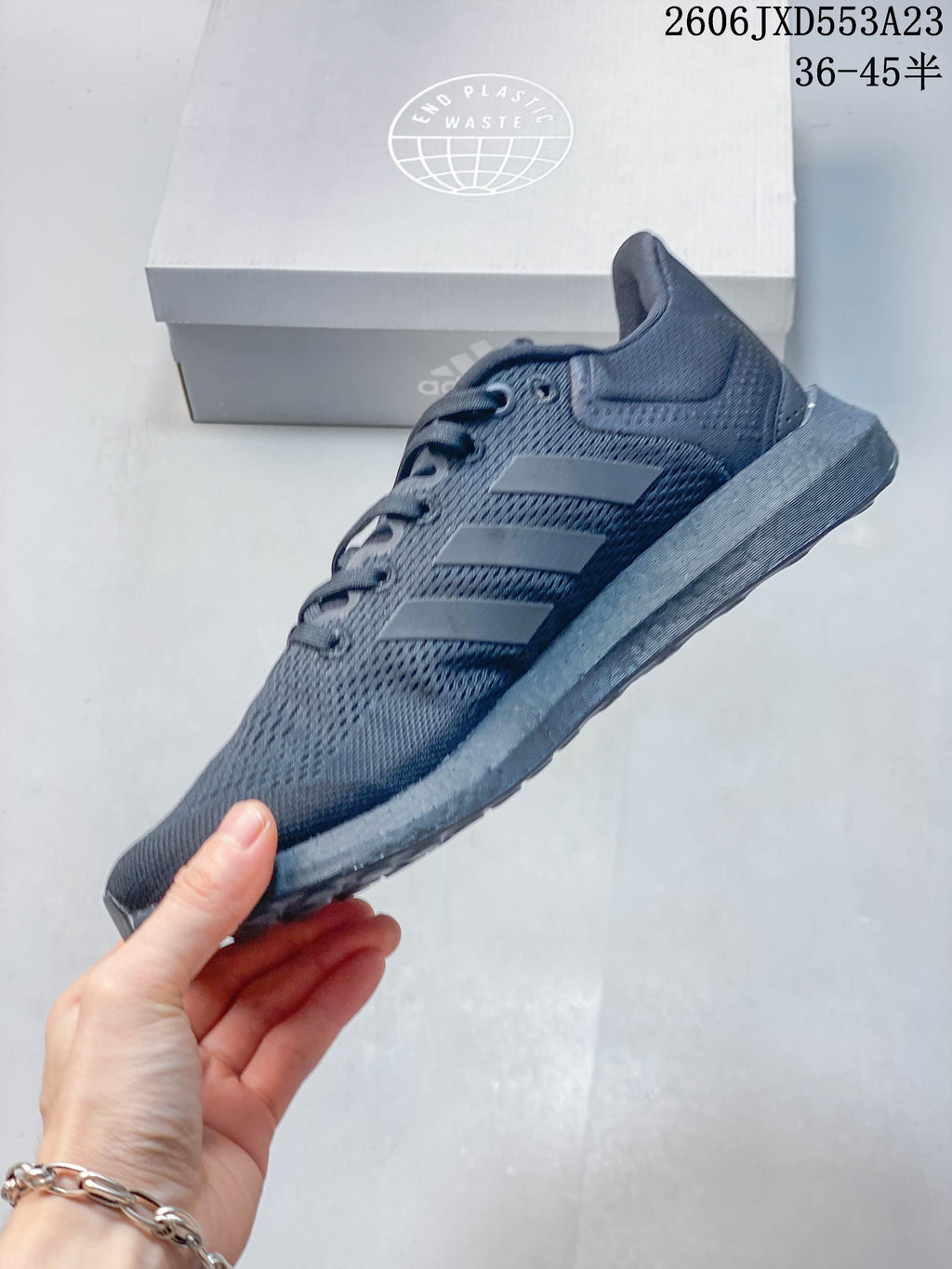Side view of a charcoal Adidas PureBoost 21 running shoe with three stripes.