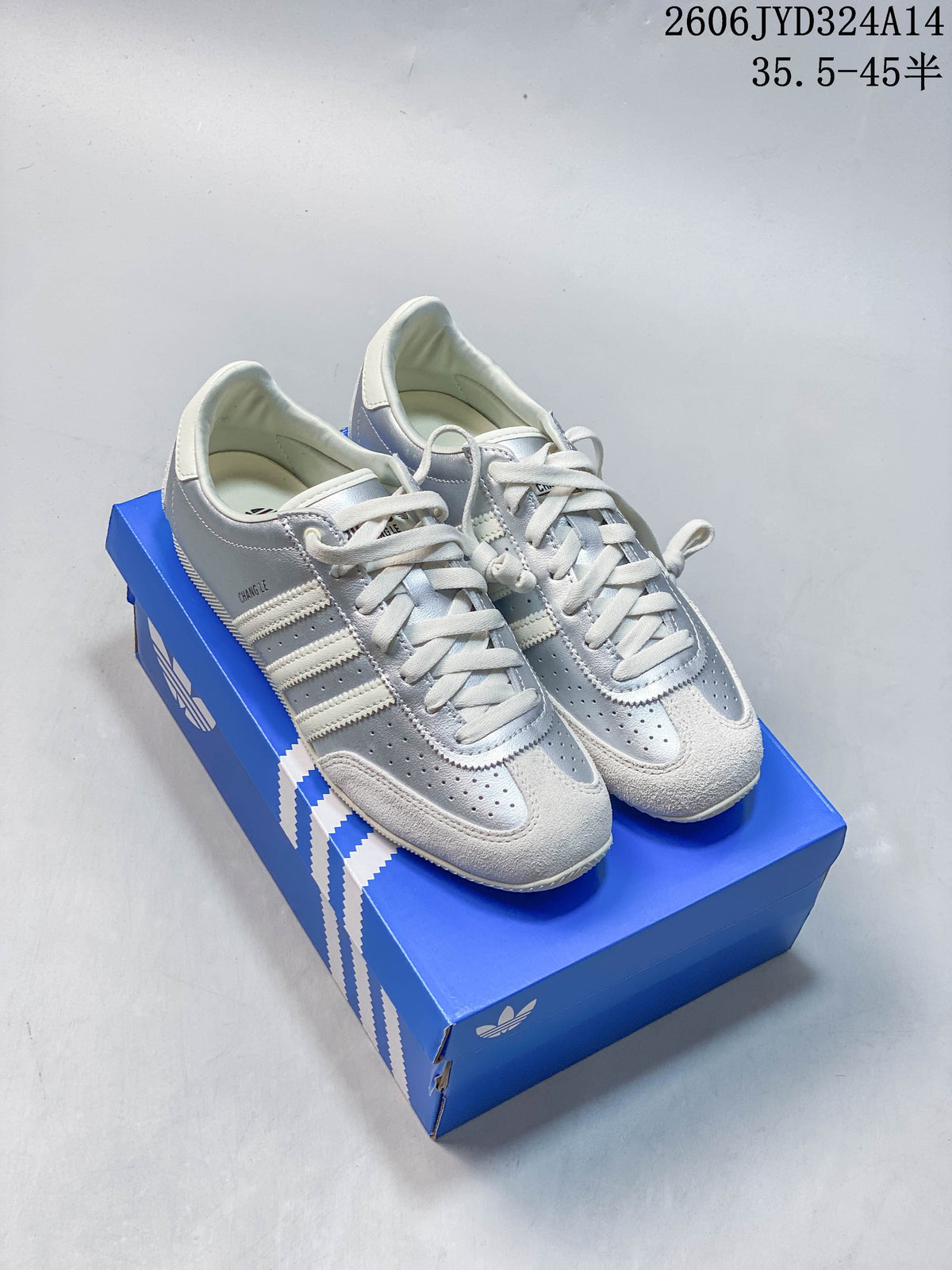 Pair of silver and off-white Adidas CHANGLE low-profile sneakers on a blue shoe box