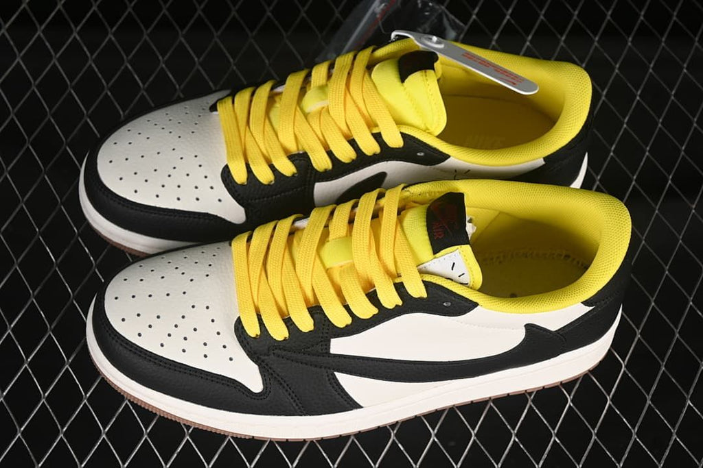 Pair of black and white low-top sneakers with perforated toe panels, yellow laces, and yellow collar lining.