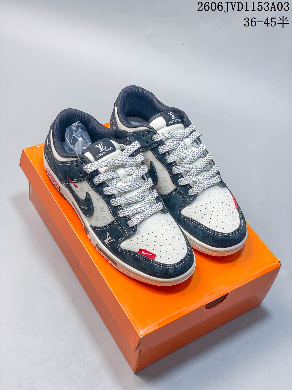 Pair of navy and off-white low-top sneakers displayed on an orange shoebox