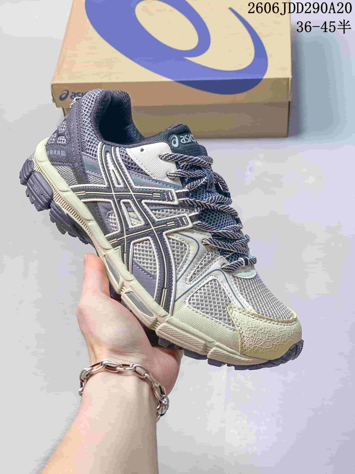 Close-up of a gray and cream ASICS Gel-Kahana 8 sneaker with a lace-up front and textured outsole.