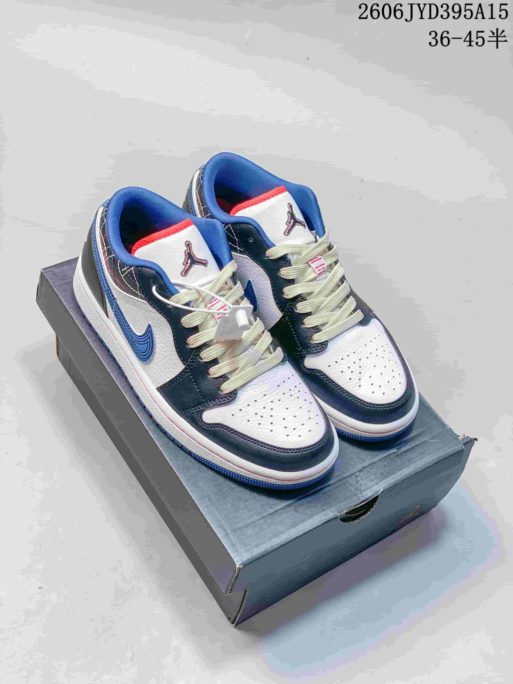 Pair of white, blue, gray, and red-accent Jordan low-top sneakers on a shoebox