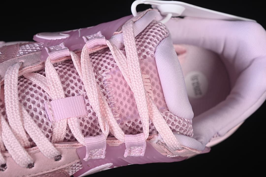 Top close-up of the pink sneaker showing the laces, mesh-look tongue and padded collar.