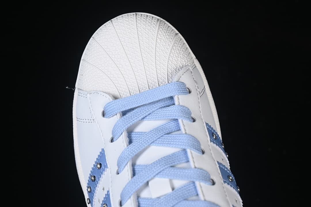 Top-down close-up of the shell toe and pale blue laces.