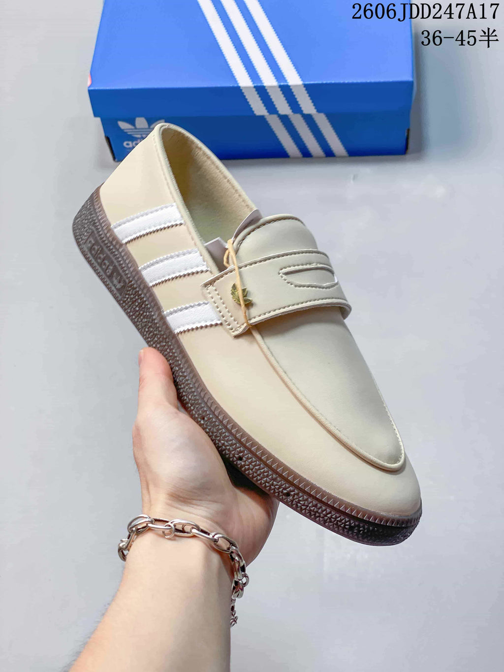 Angled side view of a cream adidas Handball Spezial shoe with white stripes and a dark textured sole
