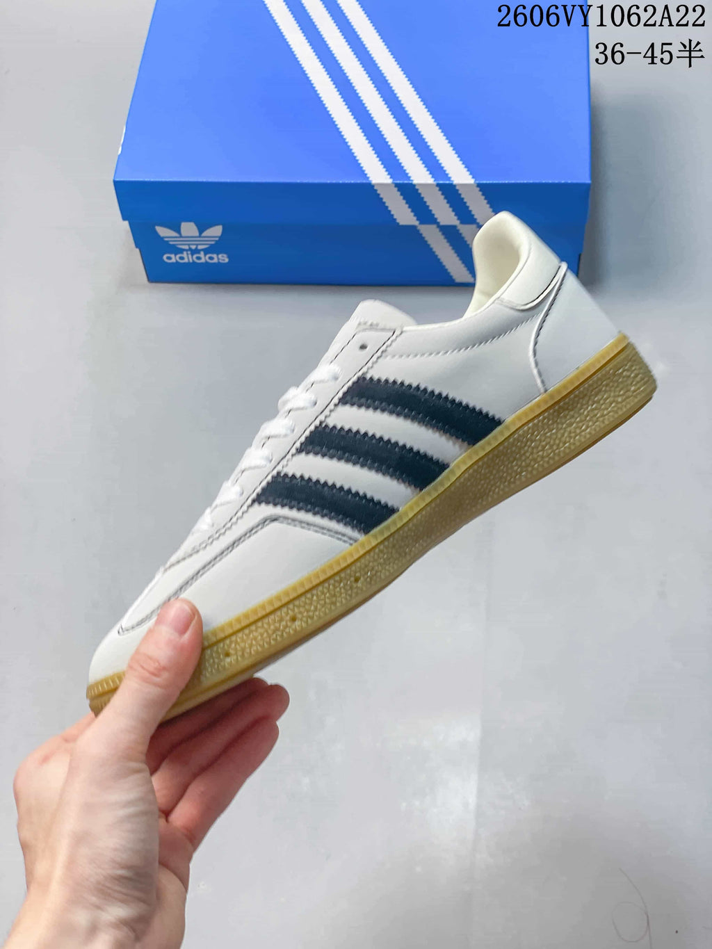 Side profile of the white sneaker with navy stripes and a gum-colored outsole