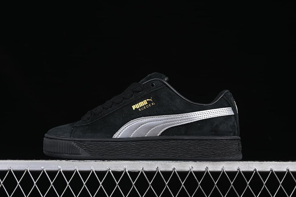Side view of a black Puma Suede XL sneaker with a silver stripe and black sole.