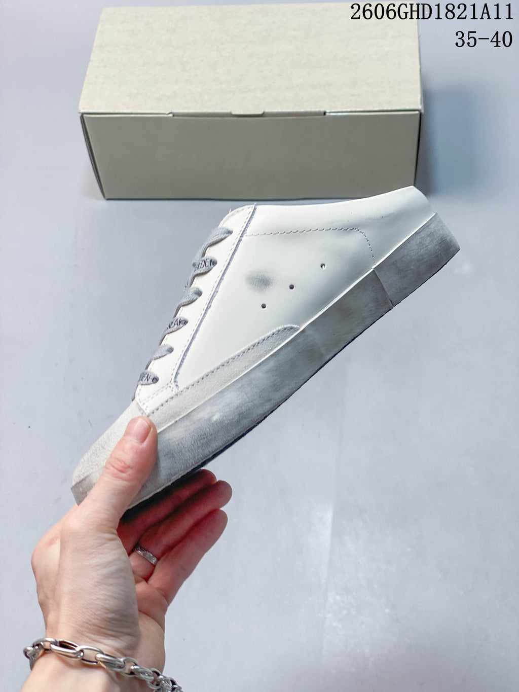 Side view of the white sneaker with a gray toe panel and distressed-looking sole.