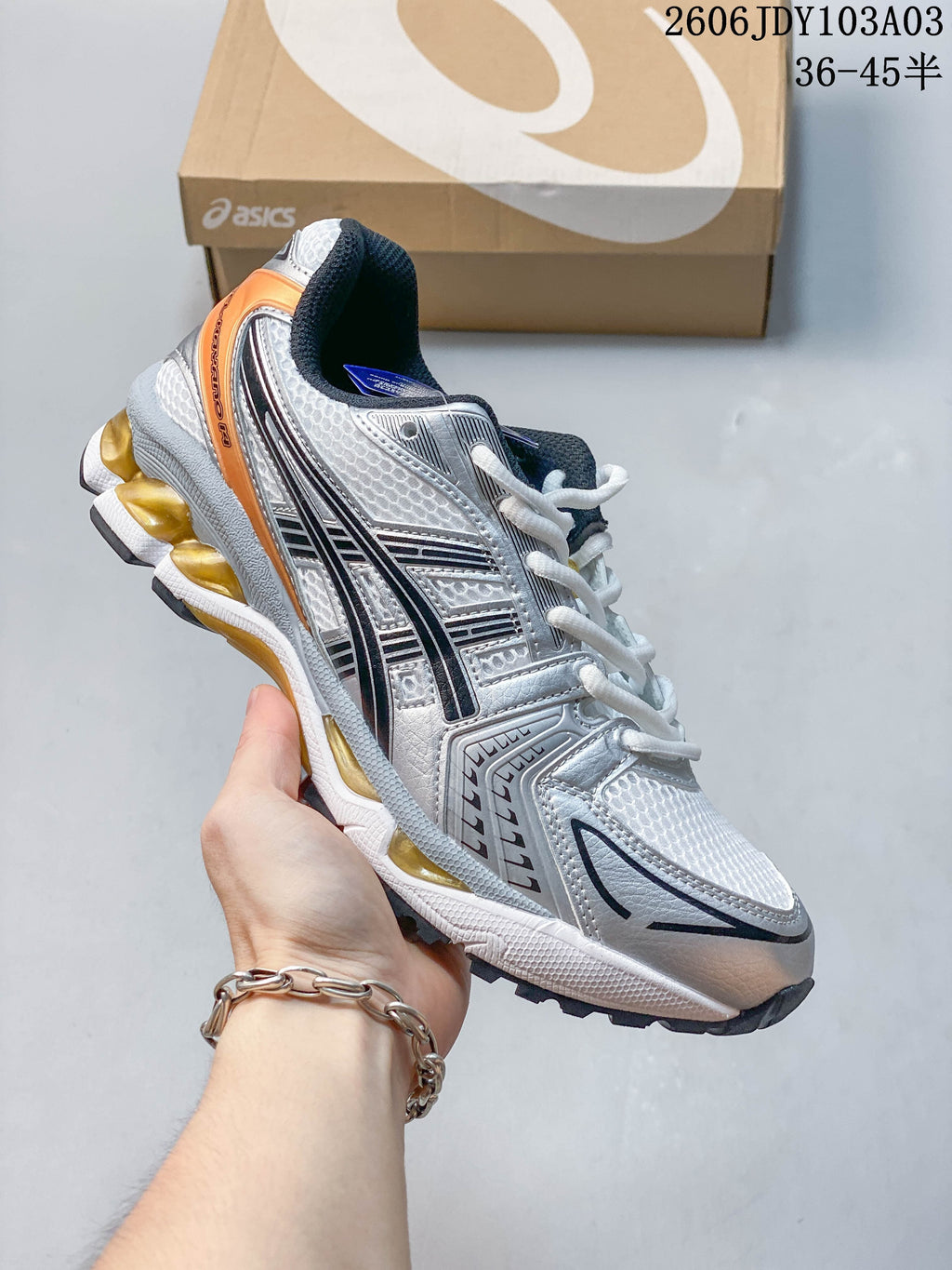 Silver and white ASICS GEL-KAYANO 14 sneaker with orange accents