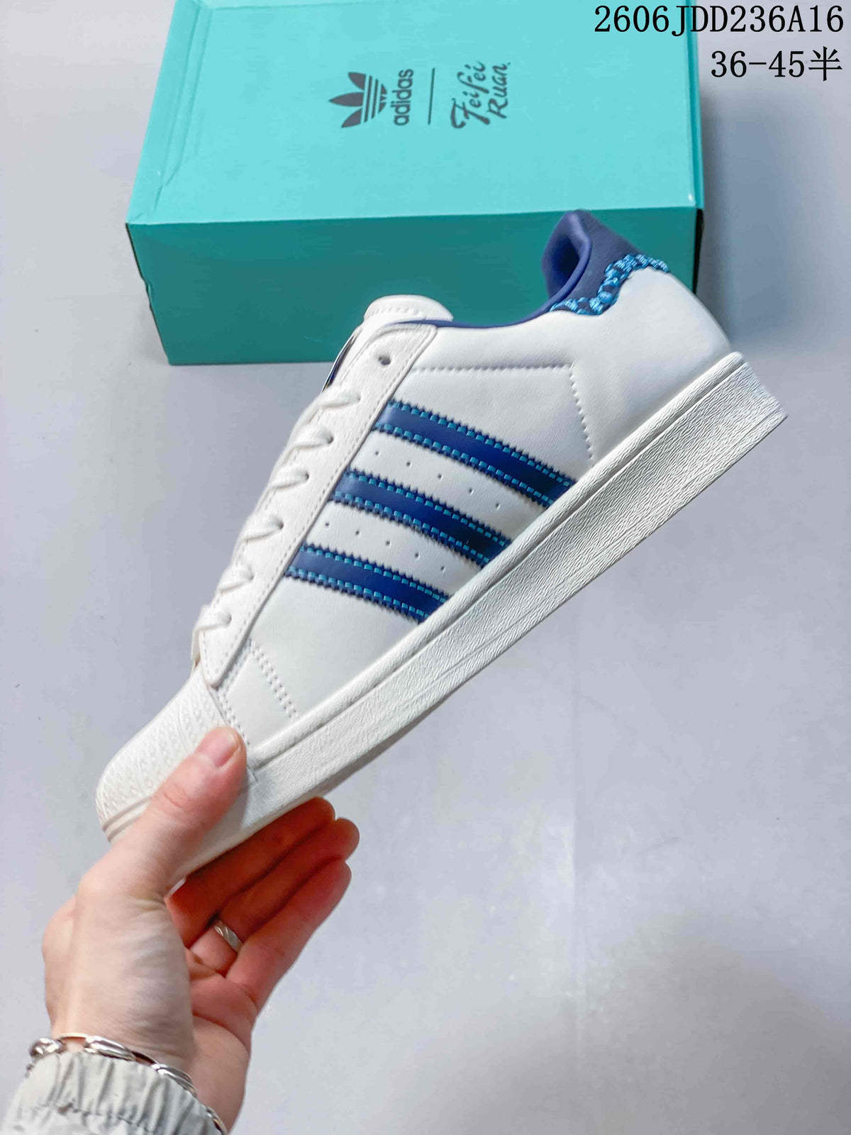 Side view of a white Superstar sneaker with blue stripes and a white sole.