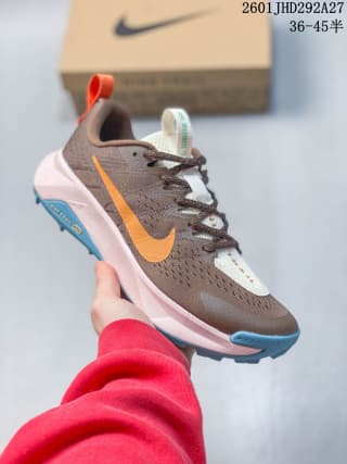 Brown Nike trail running shoe with an orange Swoosh, pale midsole, and blue outsole accent.