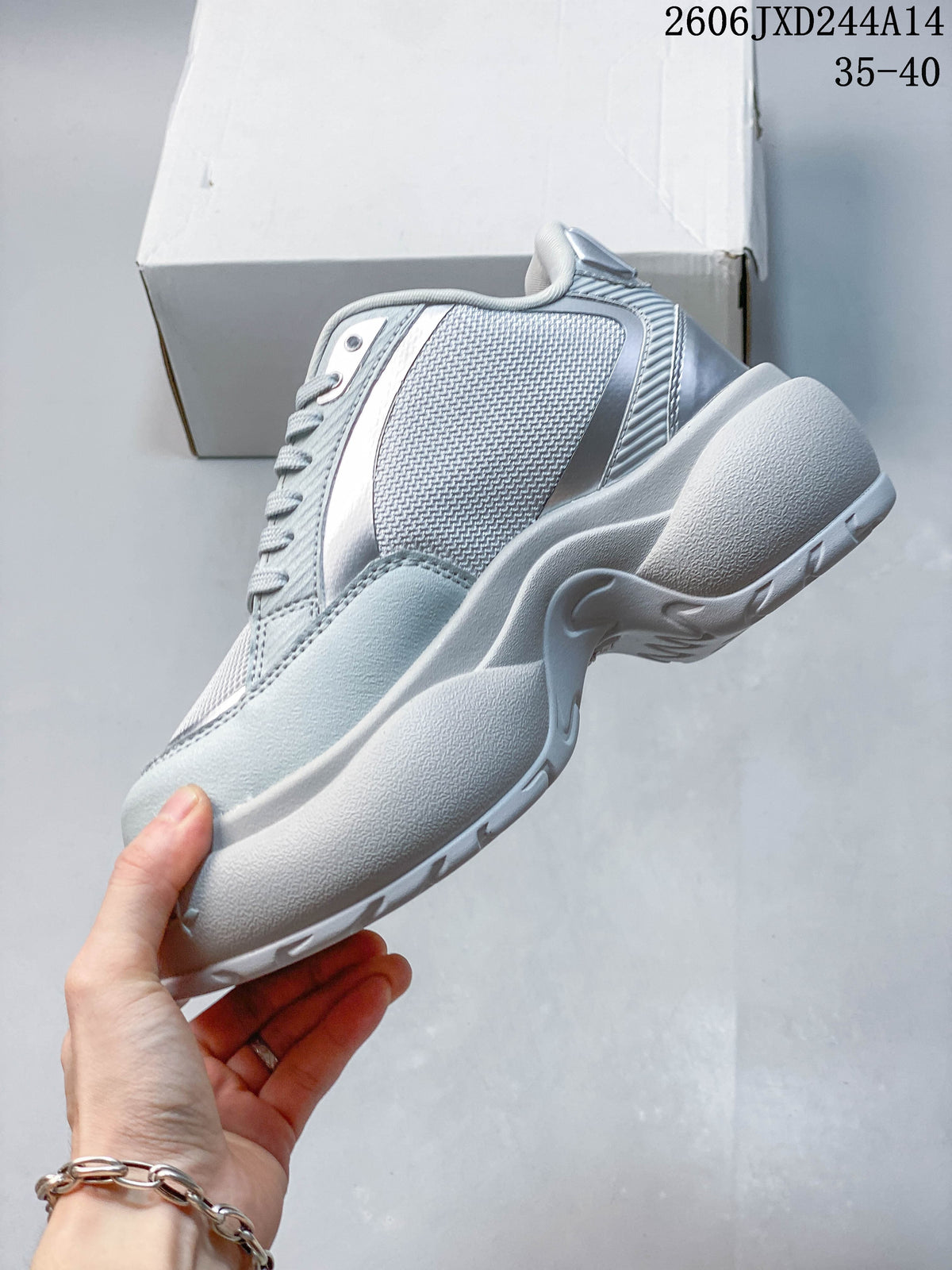 Side profile of a silver-gray sneaker with layered panels and a sculpted sole