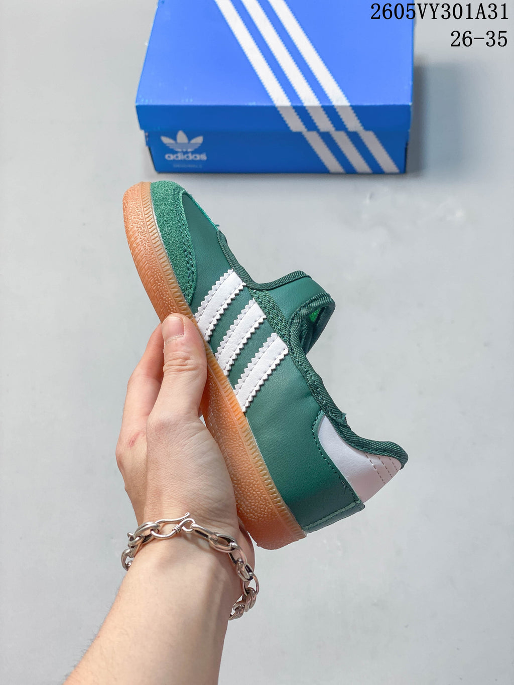 Side view of the green and white shoe with three white stripes and gum-colored outsole