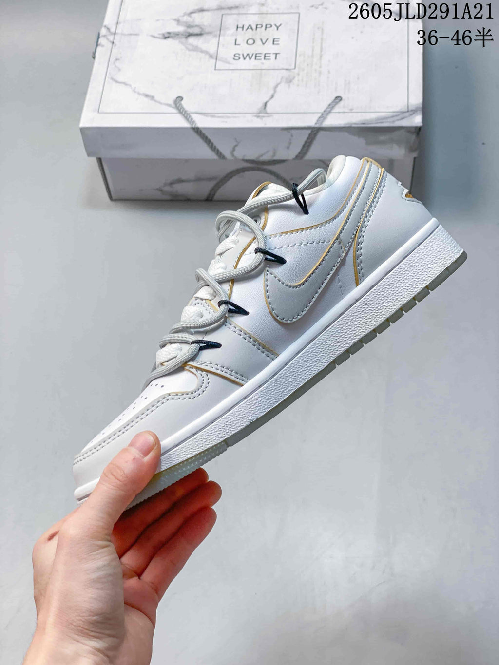 Side view of a white and grey low-top sneaker with gold-colored trim