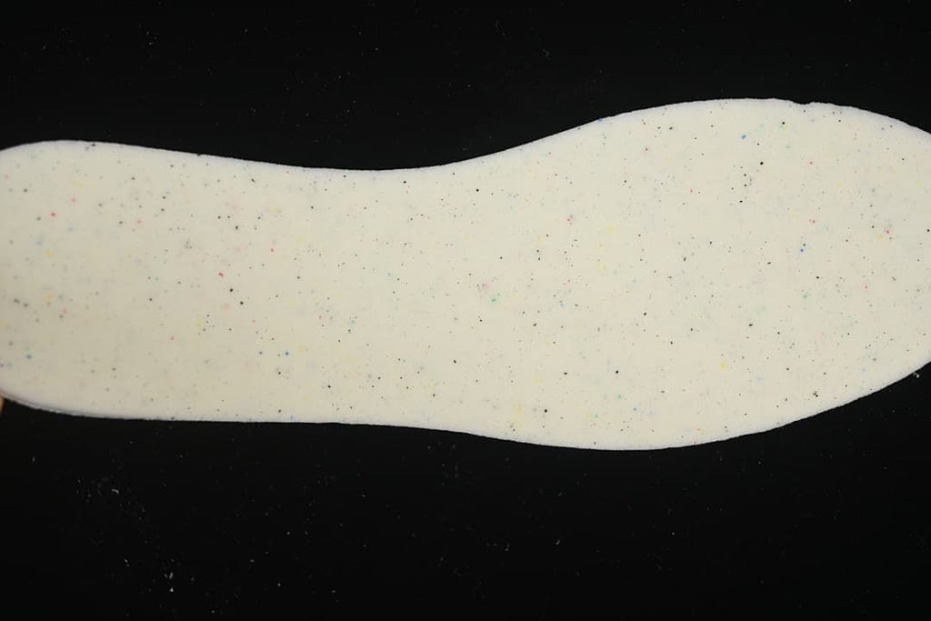 Close-up of a light-colored shoe insole with multicolor speckled details.