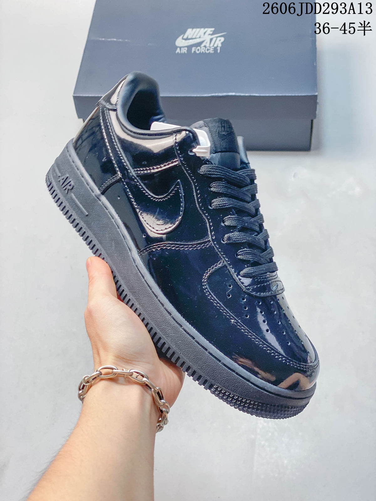 Close-up of a glossy dark low-top sneaker with side Swoosh and perforated toe; image overlay shows size range 36–45.5.