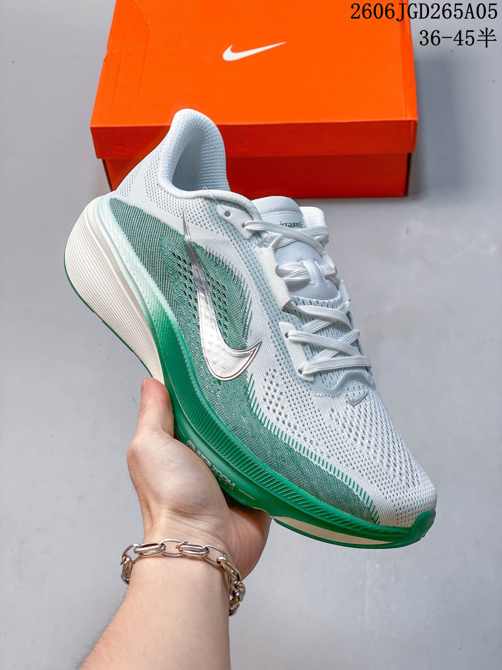 Angled side view of the white and green running shoe, with size range text visible in the image