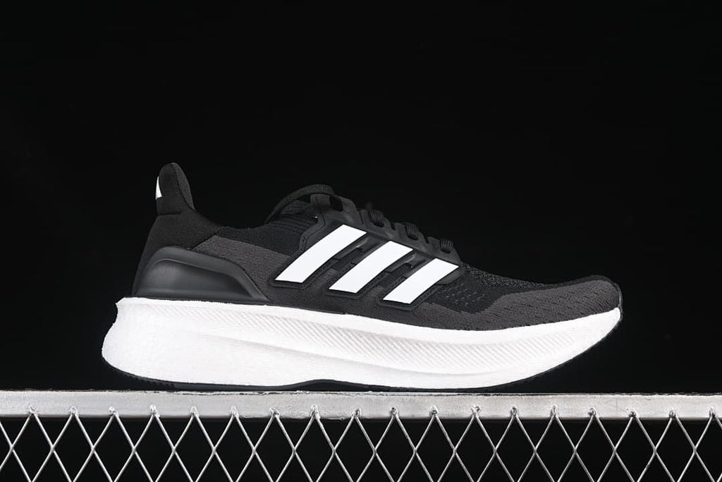 Side profile of a black and grey Adidas Ultraboost 5 with white stripes and midsole