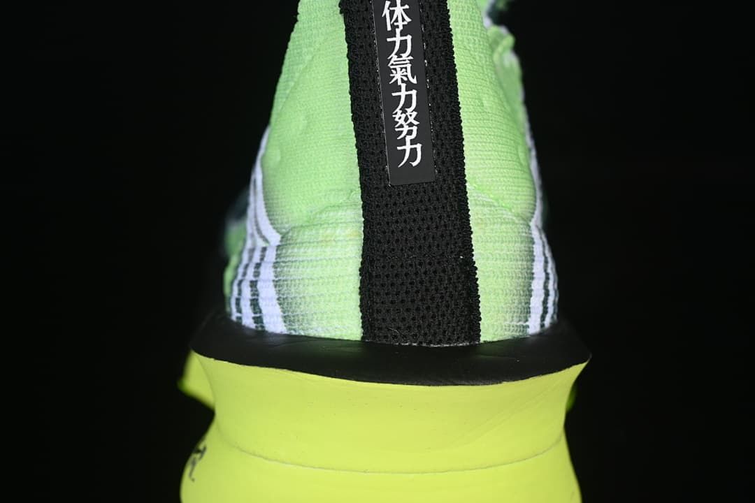 Rear view of the shoe with a black heel strip and green midsole