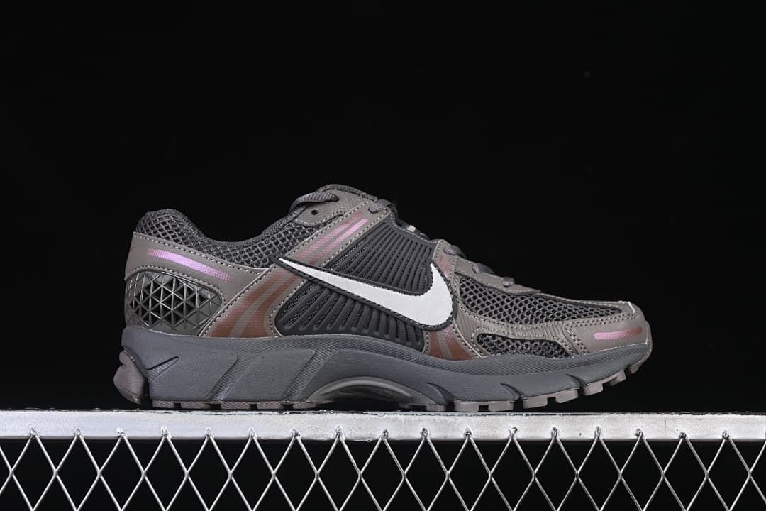 Outer side profile of a grey sneaker with white Swoosh and pink accents