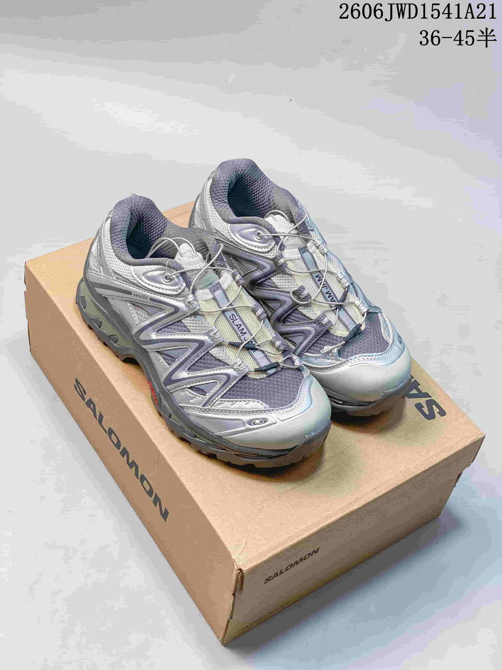Pair of silver and gray Salomon XT-Quest ADV sneakers on a shoebox; image overlay shows a size range.