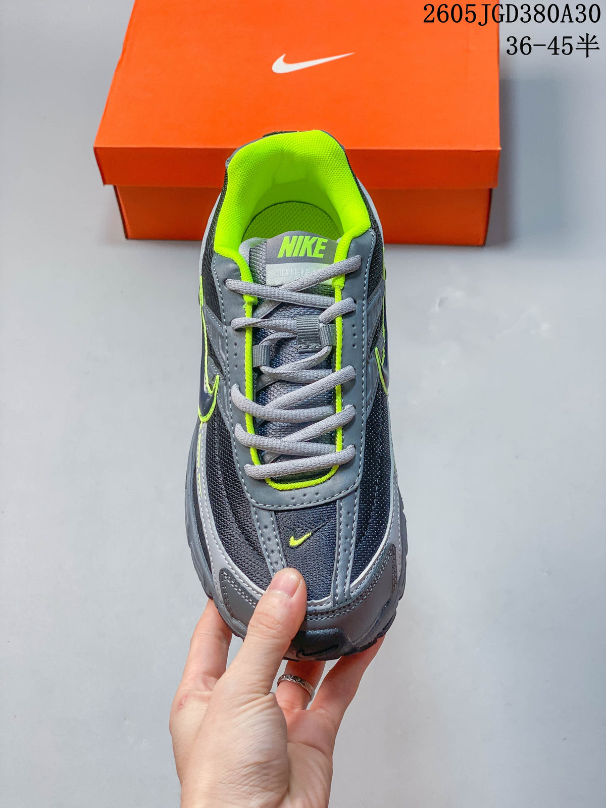 Top-down view of a sneaker showing gray laces, dark mesh panels, and a bright volt green lining.