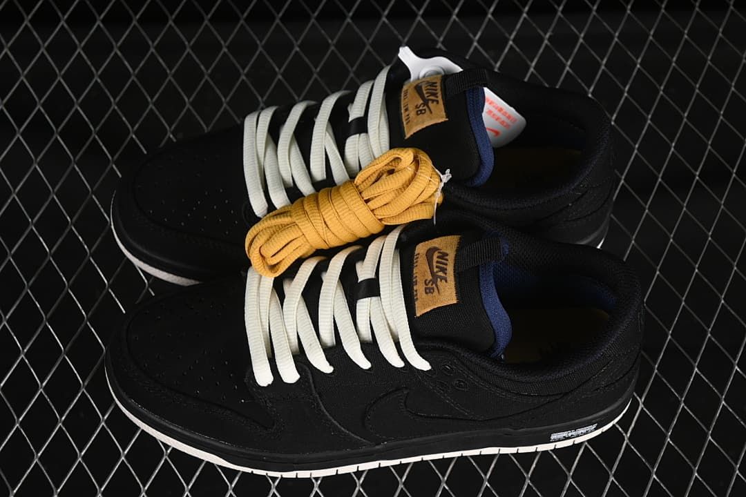 Pair of black low-top sneakers with white and golden-yellow laces