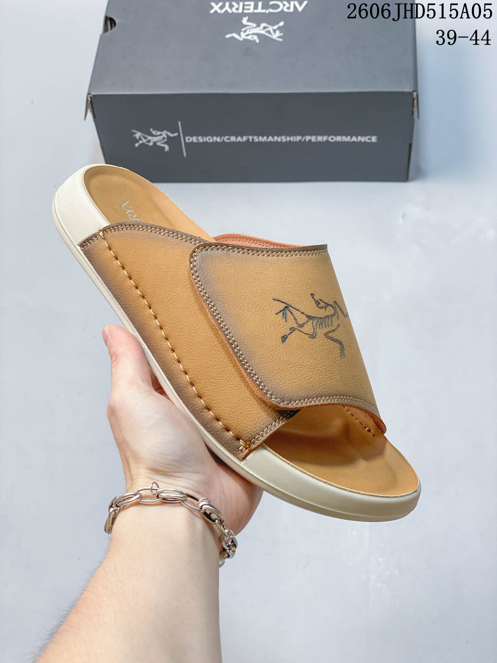 Close-up of a tan slide sandal showing its wide strap and stitched detailing.